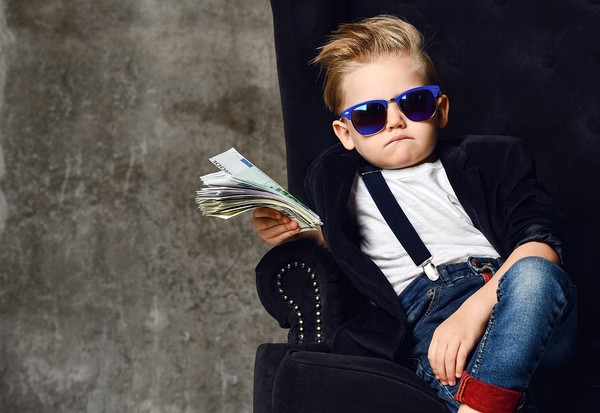 Cool child sitting in a chair with sunglasses and a stack of cash.