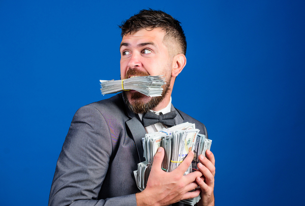 Man with stacks of cash in hands and mouth.