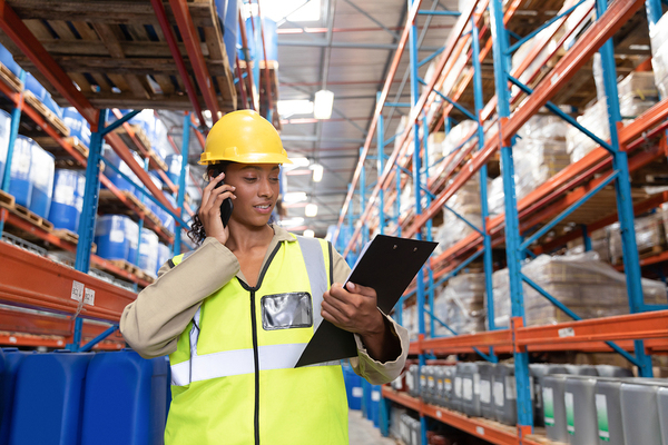 Woman wearing a yellow hard hat and reflective vest while holding a clipboard.