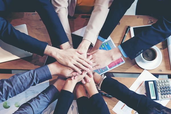 Colleagues placing hands on top of each other around a table.