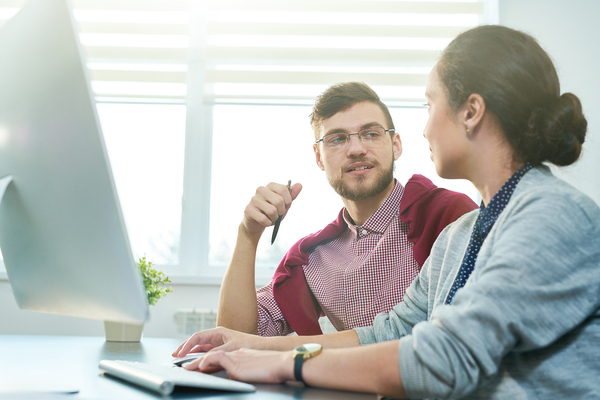 Two people in front of a desktop computer.