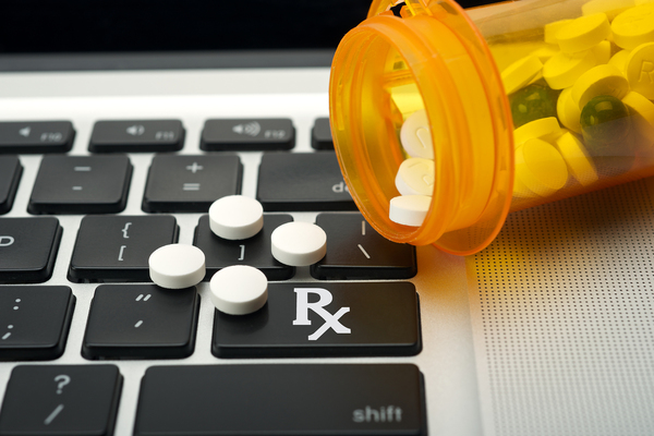 Computer keyboard with a spilled bottle of pills on it.