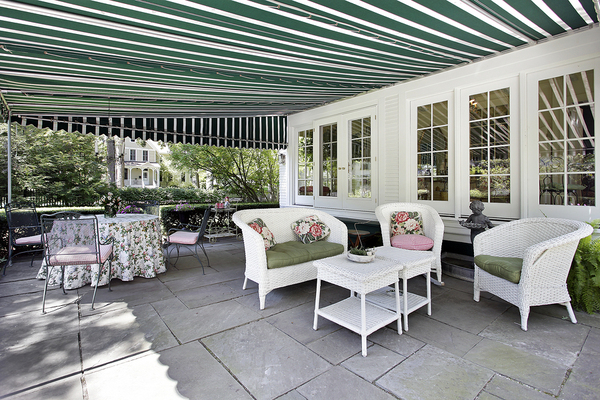 Backyard deck with patio furniture and white and green awning.