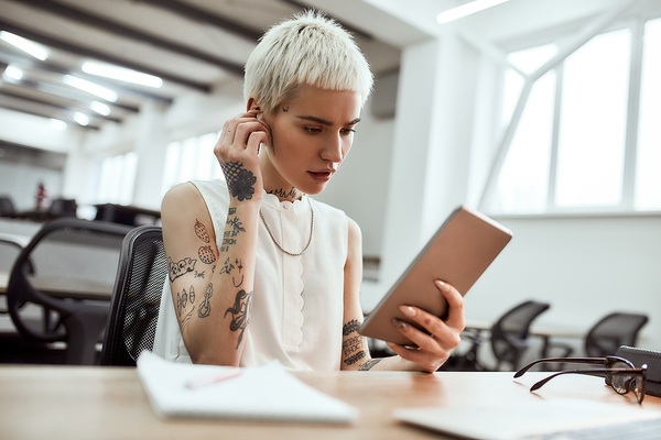 Woman sitting at a table looking at her phone.