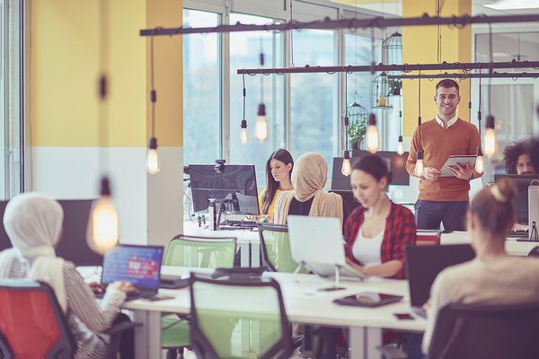 Open work space with people working at long tables.