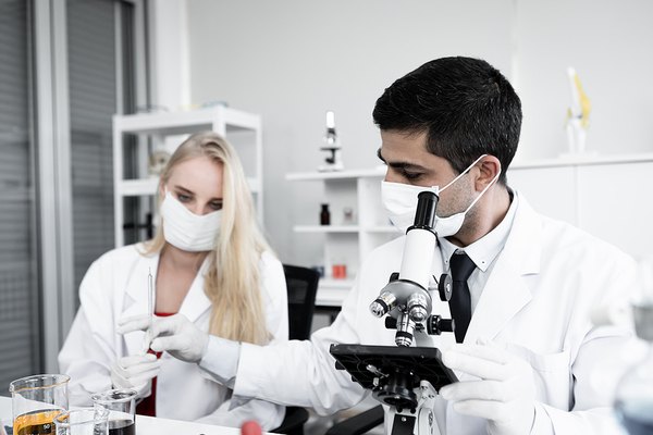 Two scientists looking at liquid under a microscope.