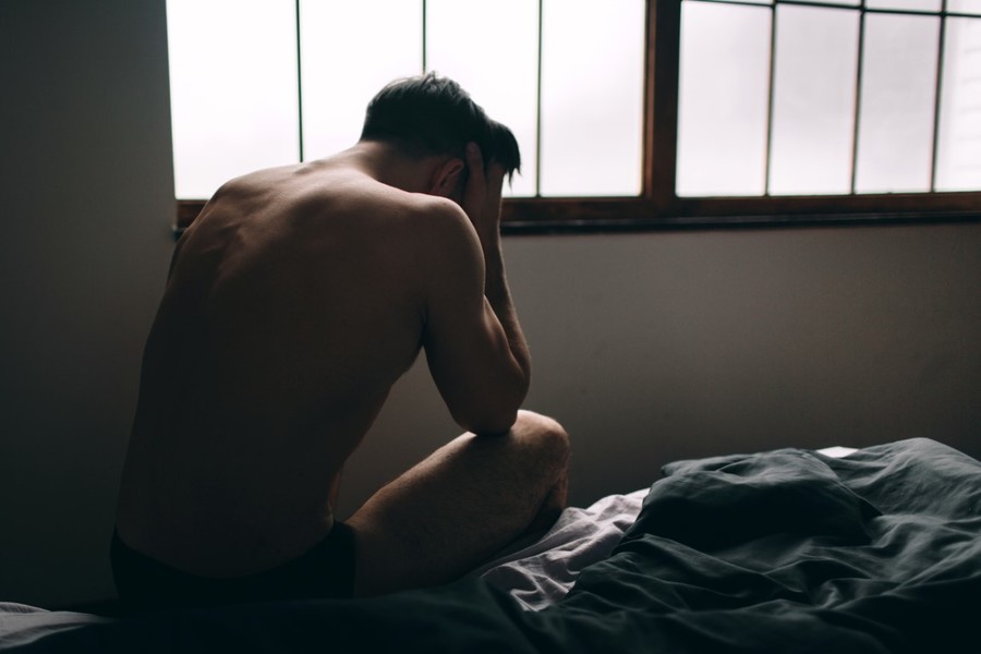 Man sitting at the edge of his bed.