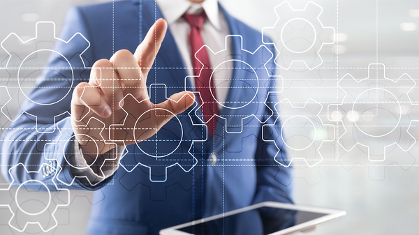 Man in a blue suit pointing to cogs.