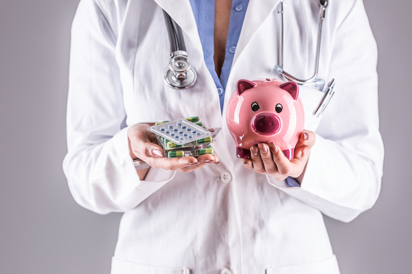 Medical doctor holing pill packs and a piggy bank.