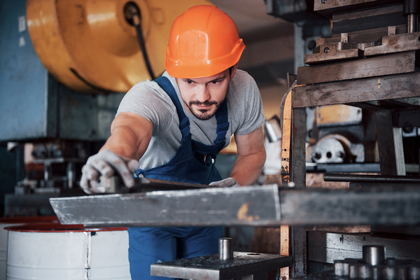 Technician wearing an orange hard hat working with machinery.