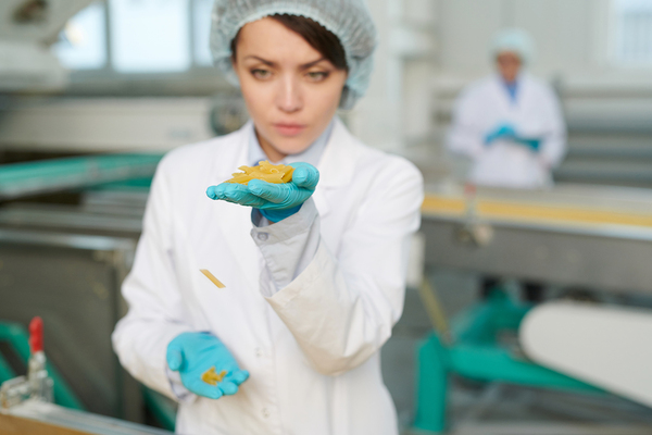 Woman inspecting food item in a manufacturing plant.