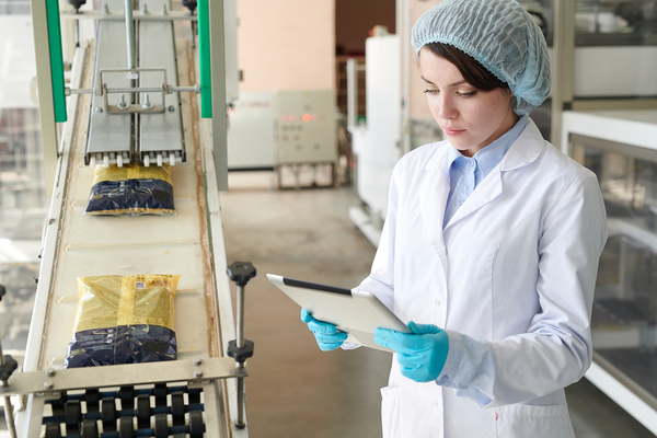 Person looking at information on a tablet in a food manufacturing plant.