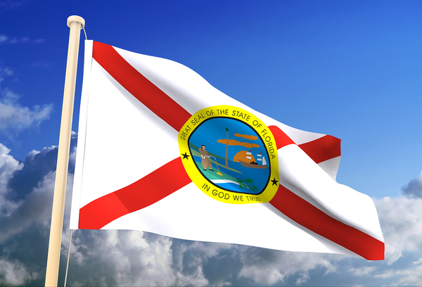Florida state flag flying with a blue sky in the background.