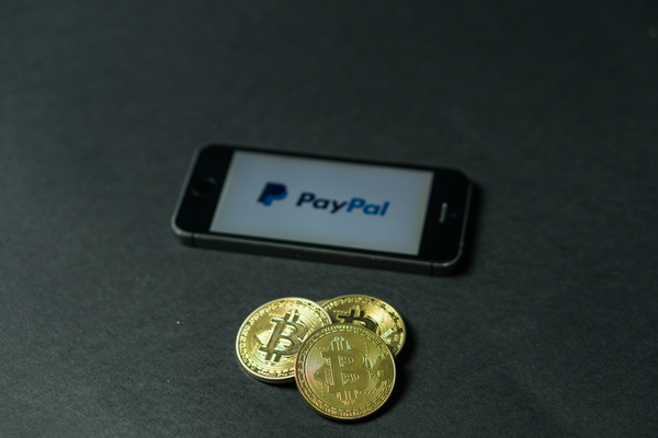 Bitcoin gold coins and a mobile phone displaying the paypal app.
