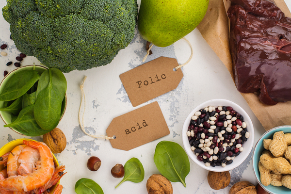 Various healthy foods on a table, broccoli, shrimp, spinach, pears and peanuts.