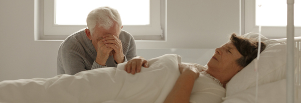Husband sitting by his wife's bed.