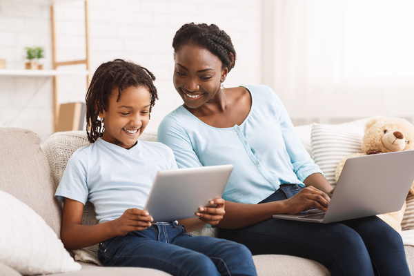 Parent and child sitting together using computers.