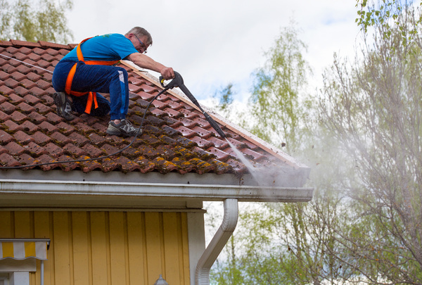 Powerwashing a roof and gutters.
