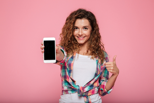 Young woman holding a smartphone with a thumbs up.