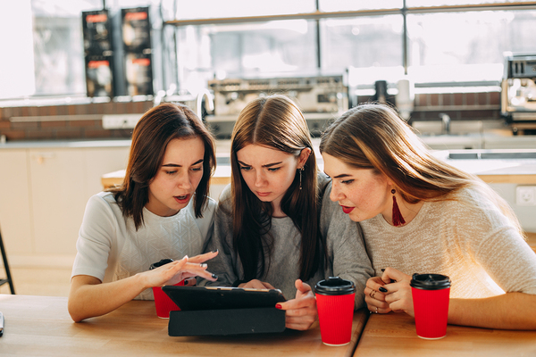 Group of teens looking at a tablet together.