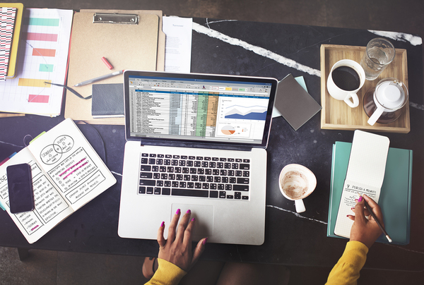 Tabletop with laptop, documents, and notebooks.