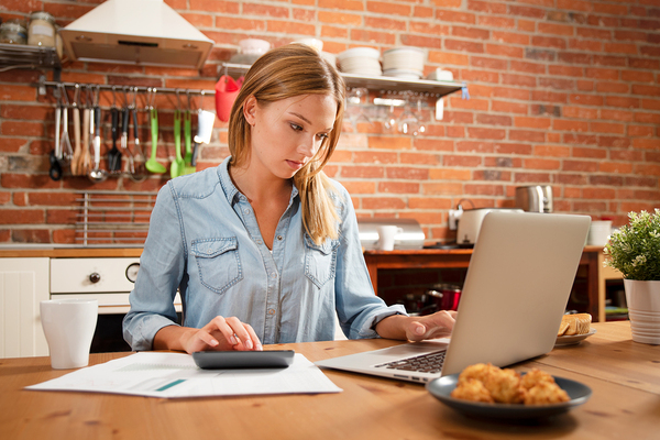 Woman working at a laptop in her kitchen.