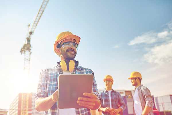 Construction workers with yellow hardhats and a large crane in the background.