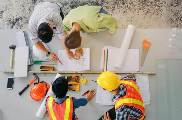 Construction men working around a table with plans.