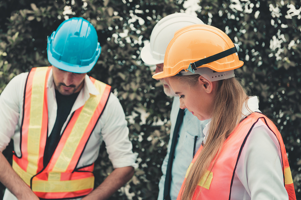 Group of people wearing hard hats and reflective vests at a construction site.