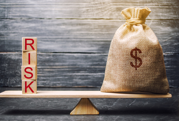 Wooden blocks spelling risk and bag labeled with a dollar sign.