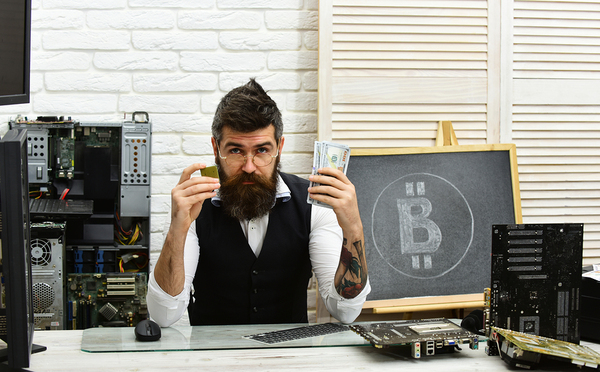 Computer technician holding cash in one hand and computer chip in the other.