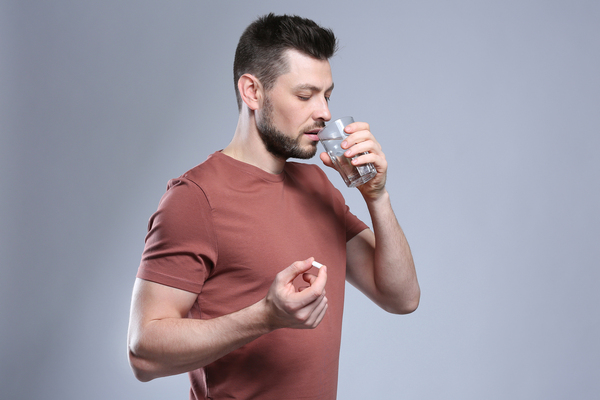Man taking an ED drug with a glass of water